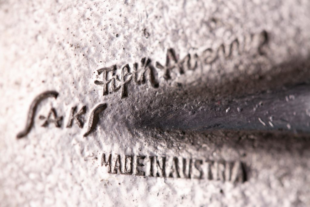 Closeup of the "Saks Fifth Avenue" and "Made in Austria" stamps on the bottom of the nickel plated horseshoe.