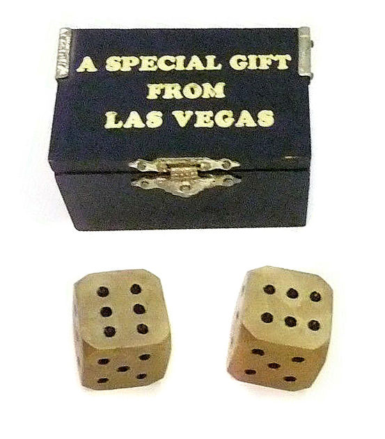 Black wooden box with "A Special Gift from Las Vegas" printed in gold foil on top and two brass dice paperweights, both with six facing up.